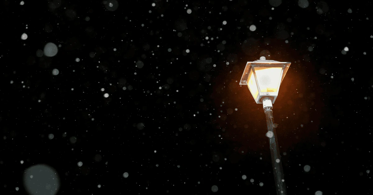 Snow falling around a glowing street lamp