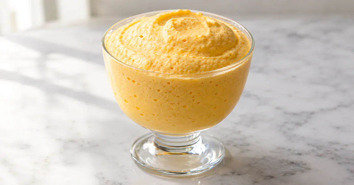 Taça de mousse de maracujá com três ingredientes, textura aerada, apresentada em copo de vidro sobre superfície clara